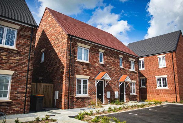 Modern red brick townhouse in Bedford, United Kingdom with public car park and shrubs