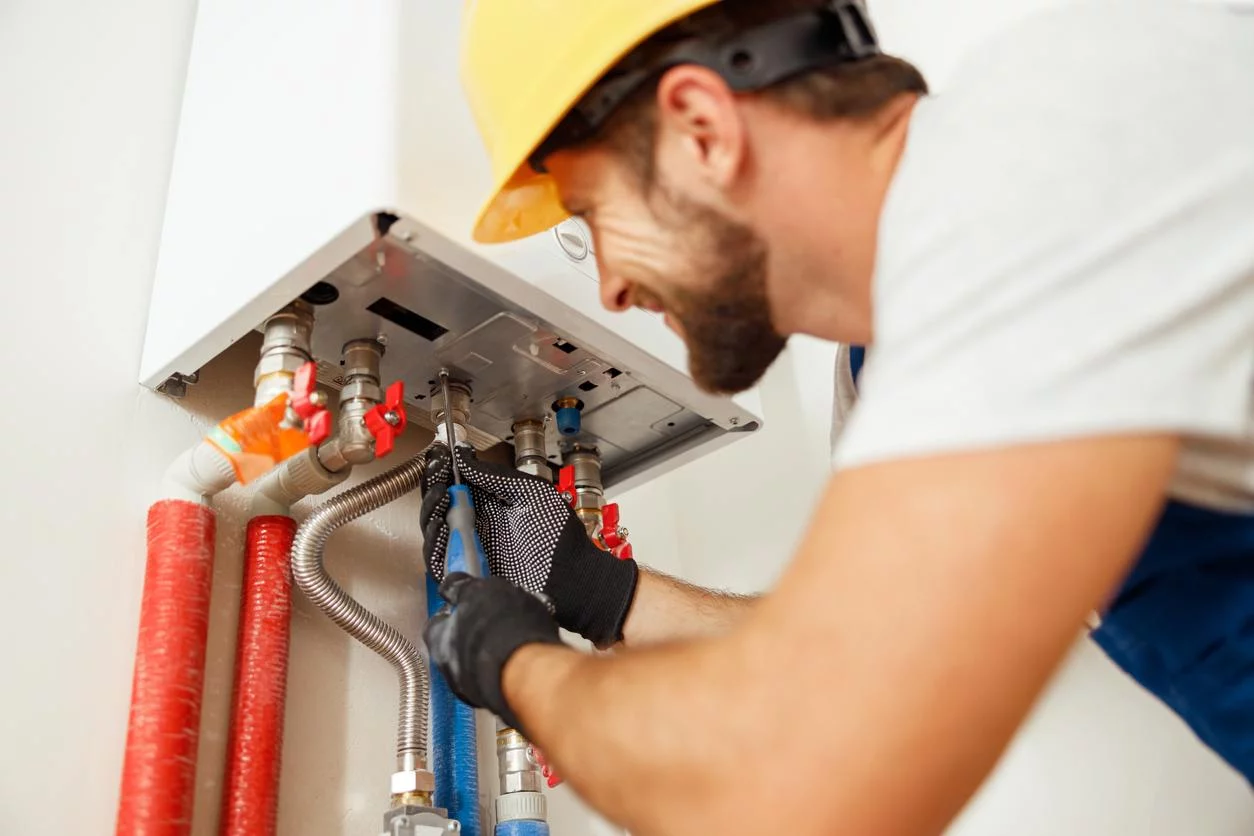 Closeup of gas boiler service professional using screwdriver while fixing boiler.