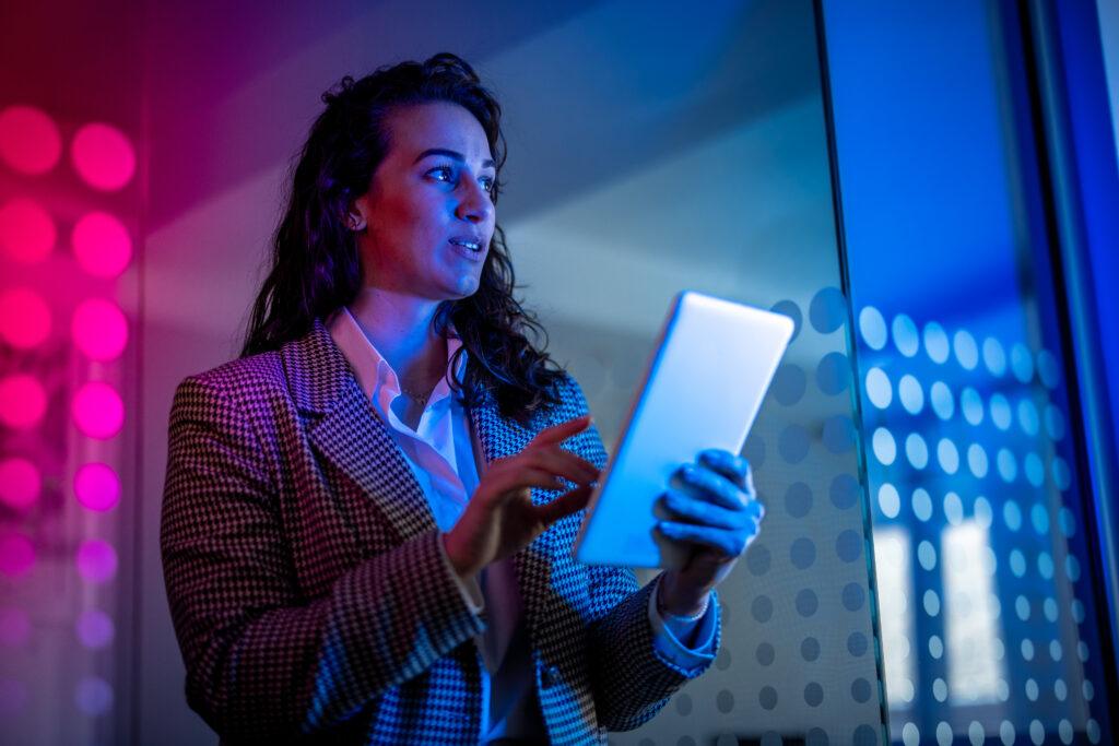 Young female field service professional in modern office setting holding tablet computer.