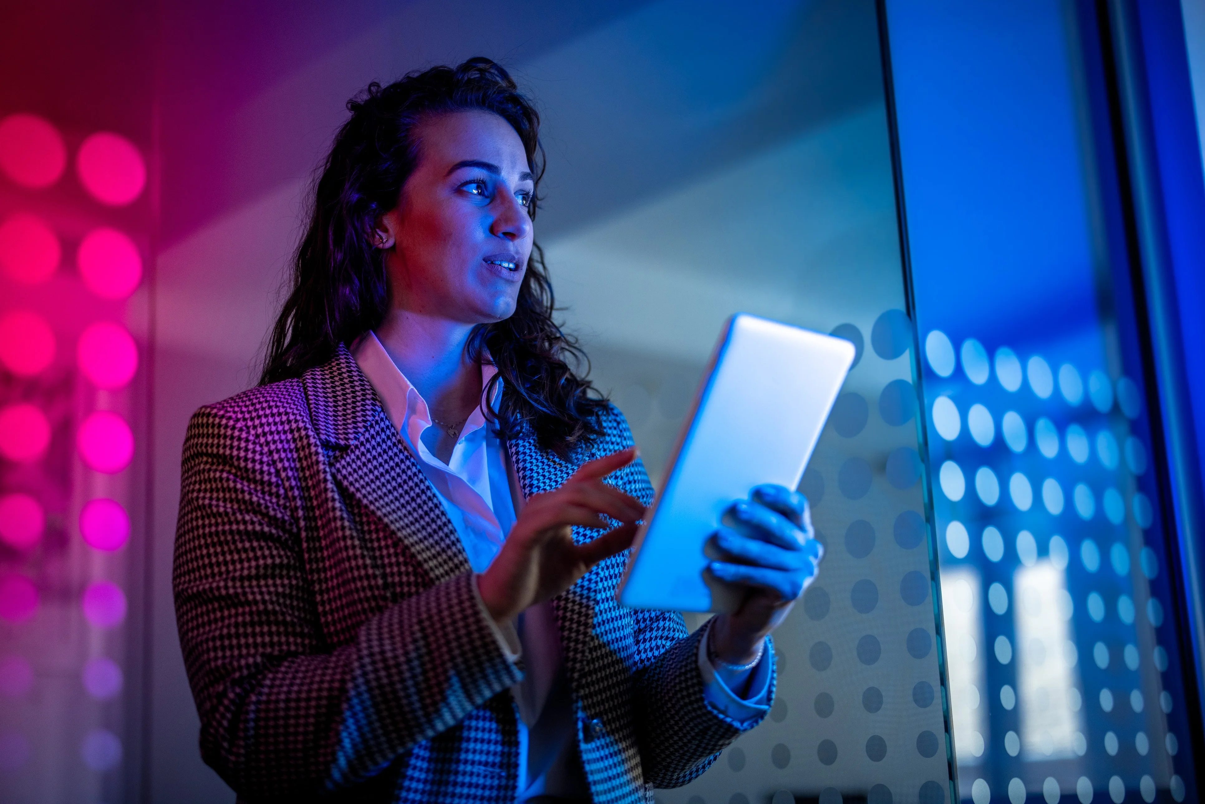 Young female field service professional in modern office setting holding tablet computer.